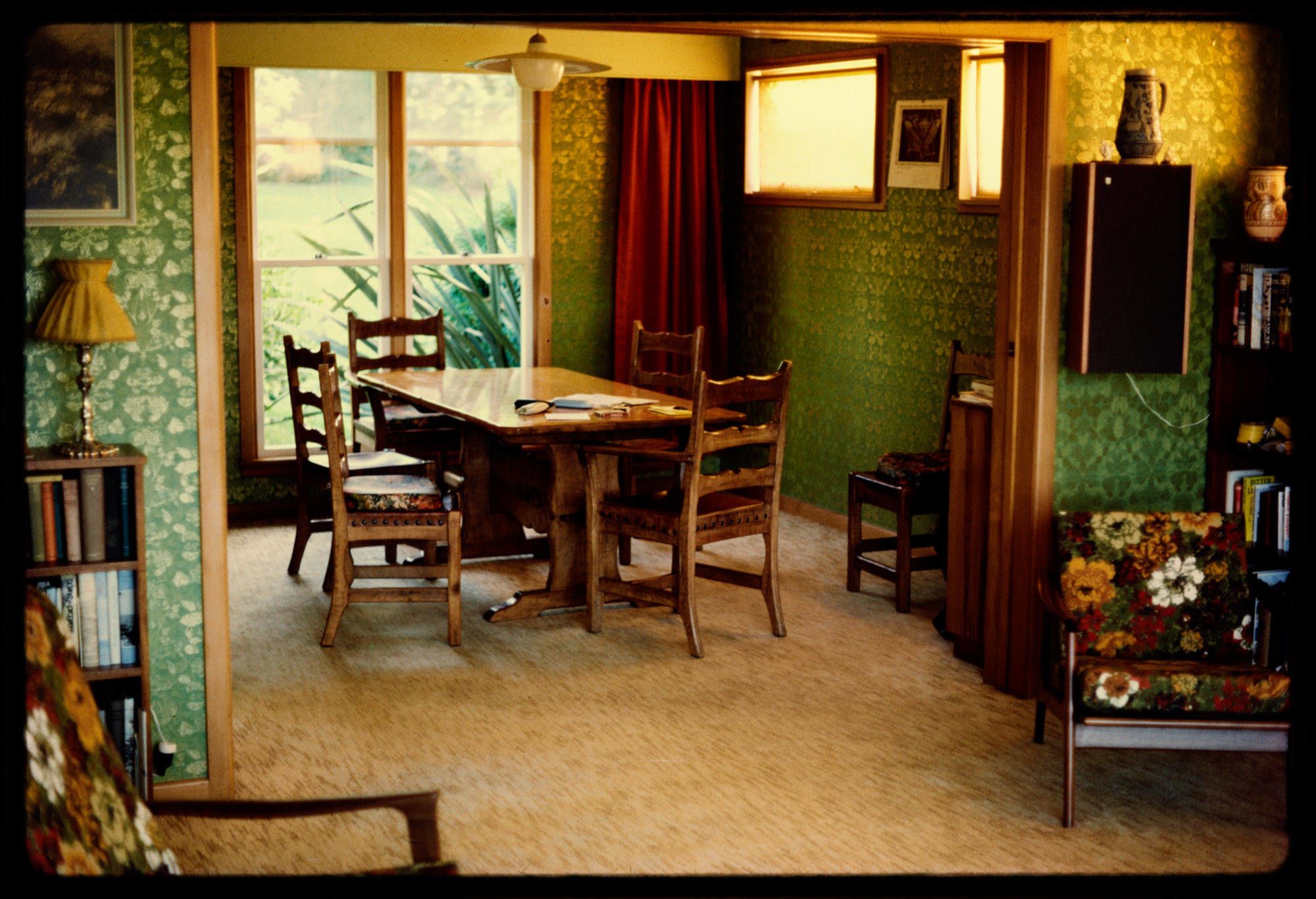 A '70s dining room with green wallpaper and floral chairs.