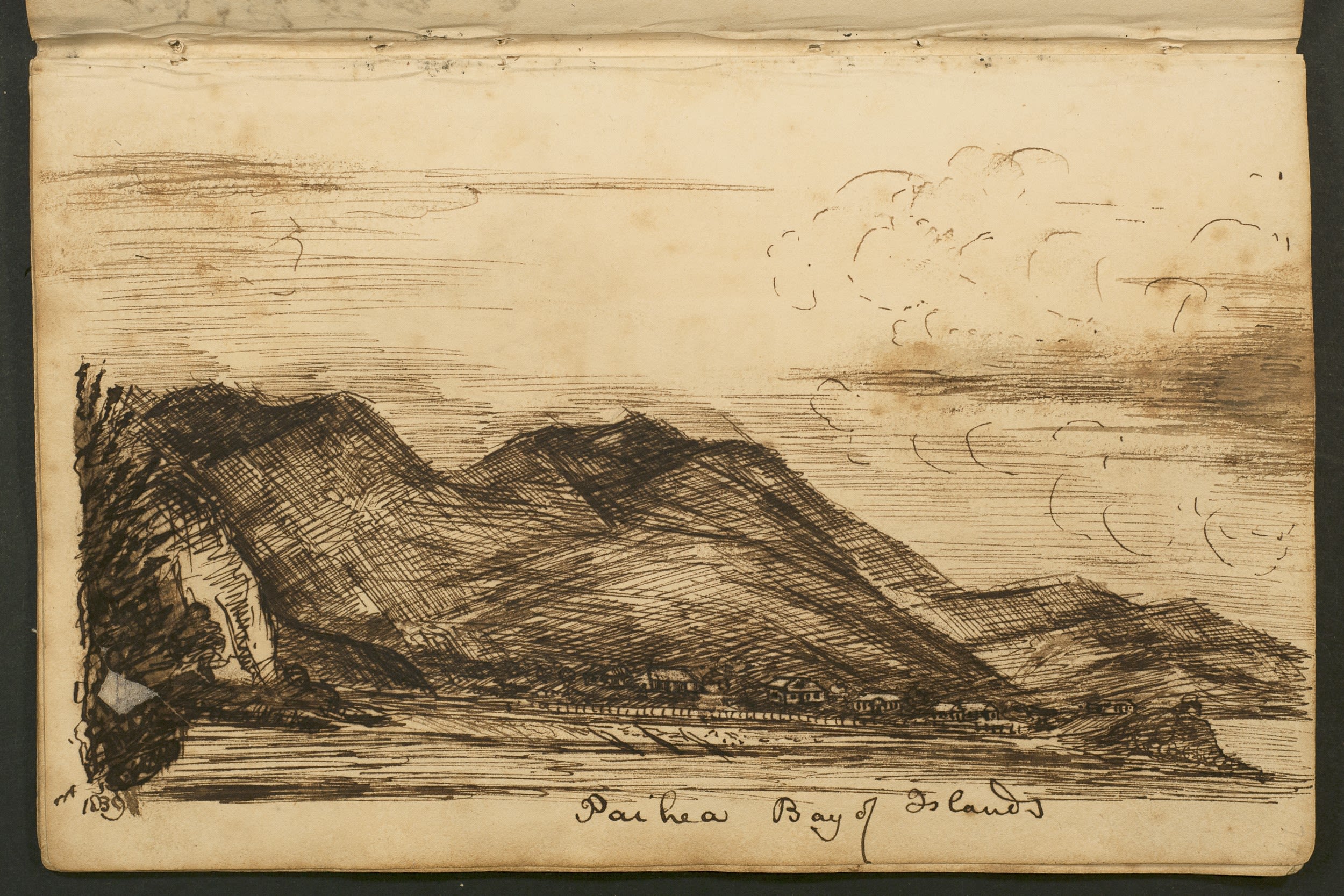 A dark sketch of a hillside and beach front on sepia paper. Tiny houses can be seen near the water.